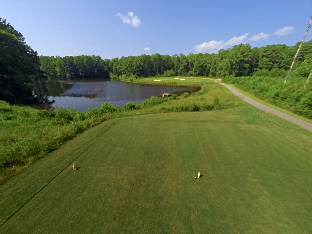 Golf course hole with tees in foreground and pond and bunkers in background