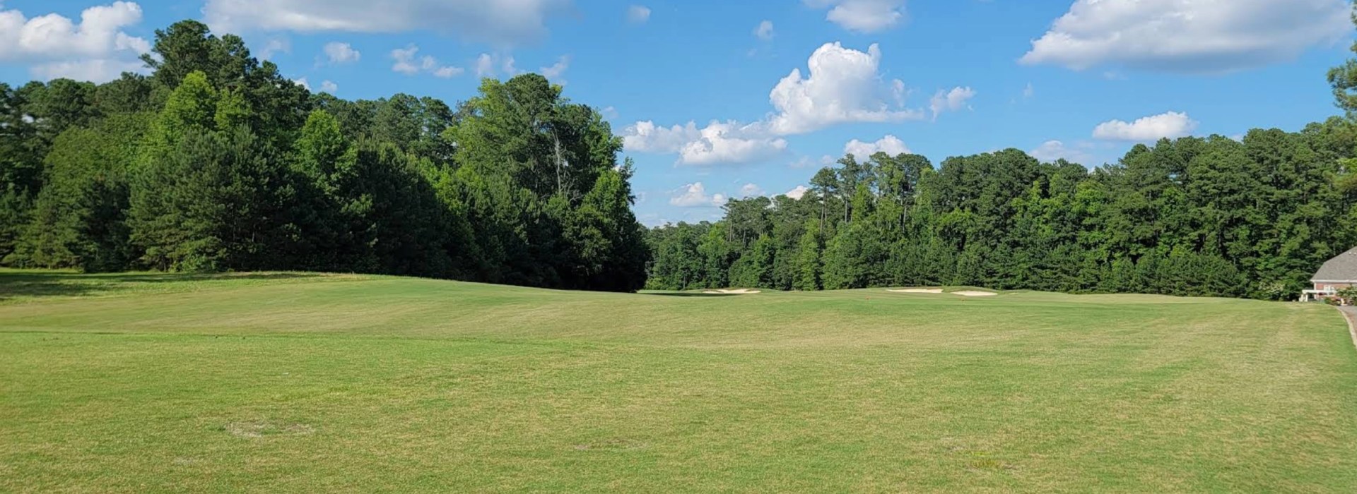 Wide fairway under blue sky and clouds at Belmont Lake Golf Club