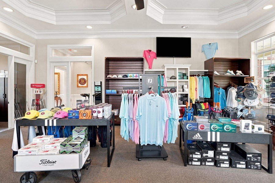 Golf shop display of Titleist golf balls, adidas shoes, and polo shirts on racks and tables
